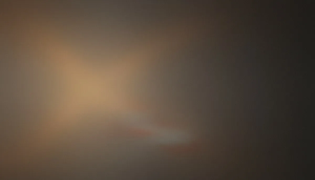 A muted mesh gradient drifts from grayed amber and dusty gold on the left into deep charcoal shadow at the right edge, a soft diagonal sweep suggesting blocks sliding down a curve, the whole frame veiled in heavy film grain.