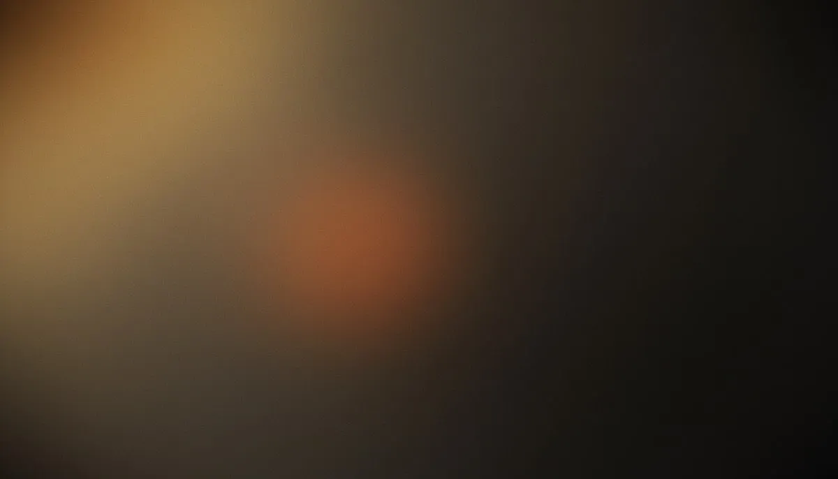 A muted mesh gradient drifts from grayed amber and dim gold in the upper left into dense charcoal darkness at the lower right, with a faint desaturated burnt-orange warmth blooming silently from the centre, the whole surface veiled in heavy analogue film grain.
